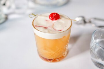 An amaretto sour cocktail topped with maraschino cherry at a French bistro-style restaurant in Circular Quay, Sydney — New South Wales, Australia