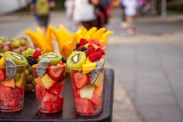 Rows of fresh cut fruit in plastic cups at urban street vendor stand