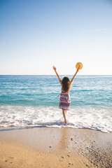a girl in summer in a dress and hat on the ocean shore with her feet in the sea wave