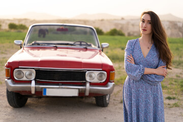 beautiful girl in retro style posing near vintage red cabriolet car.