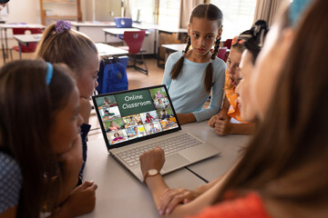 Fototapeta premium Asian female teacher and diverse students having a video conference on laptop at school