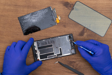 hands of the master in blue gloves, change the broken glass on the phone
