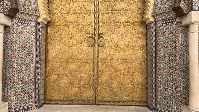 Beautiful entrance gate to the Royal Palace with mosaic and brass door in Fez, Morocco.