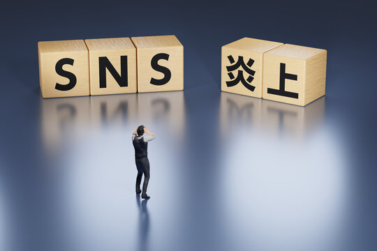 SNSが炎上して頭を抱えるビジネスマン / 匿名による誹謗中傷・違法行為の動画投稿・ネットリテラシーの欠如