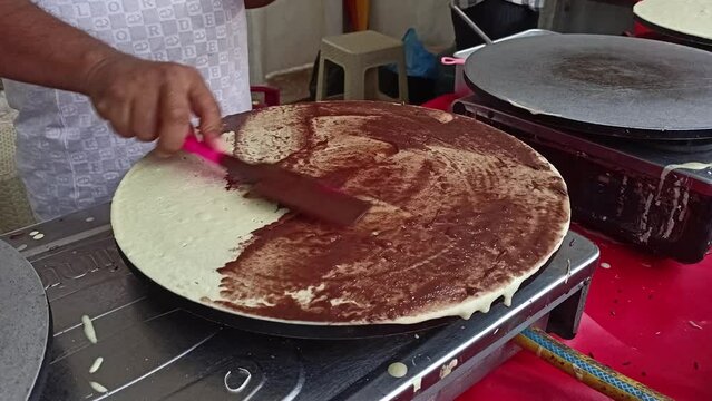 Woman cooking delicious crepe in electric pancake maker in kitchen.