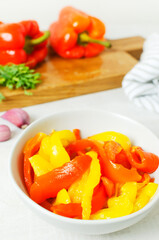 The process of preparing a salad with large red and yellow roasted peppers. Concept Traditional Italian dish. Vegetarian and vegan food. Vertical orientation.
