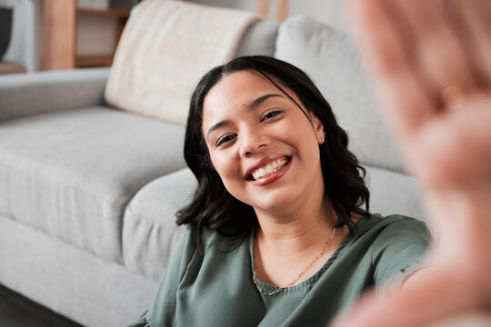 Selfie, happy and portrait of a woman in her living room relaxing, resting or chilling by the sofa. Happiness, smile and young female person from Mexico taking a picture at her modern home apartment.