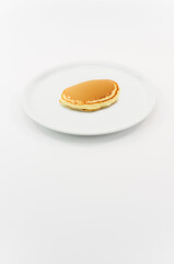 immagine primo piano di pancake su piatto in porcellana bianca, vista dall'alto su superficie bianca