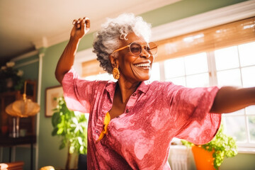 Positive black older woman dancing at home. Happiness and well being concept.