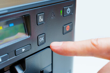 Obraz premium Hand Activates OK Button on Printer in Close-Up