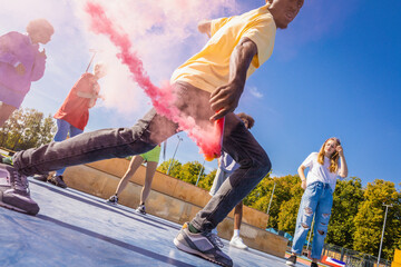 Multiracial group of young friends bonding outdoors - Cool hip hop urban dancers making a dance choreography and using colorful smoke 
