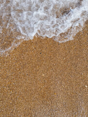 sand and wave of the sea on the beach, closeup. view from above