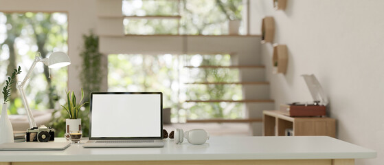 A modern home office workspace with a laptop and accessories on a white tabletop.
