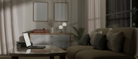 Rear view image of a laptop on a coffee table in a modern and comfortable living room at night.