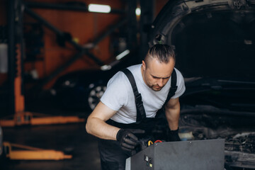 Car mechanic with manometer to fill the gas in the car air conditioning compressor. Service of checking the car air conditioner. Refrigerant recharge system.