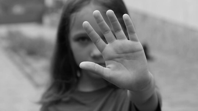 Defocused photo Girl showing stop sign gesture black and white photo. The child shows a palm, selectively focuses on five fingers. stop sign with hand saying no to domestic violence or abuse