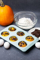 Pumpkin muffins baked in the silicone mold at the table with ingredients.