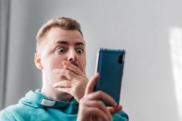 Shocked and surprised man looking smartphone. Close up portrait.