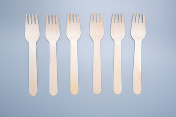 Wooden disposable fork on a gray background close-up. Environmentally friendly product.