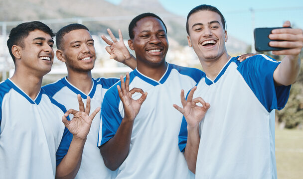 Men in selfie, OK hand sign and soccer competition, sports and athlete group on field, diversity and emoji. Happy, young male football player and team smile in picture, gesture and social media post
