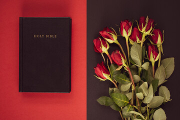 Holy Bible and red roses on the black and red background. Christian concept, believe and faith for...