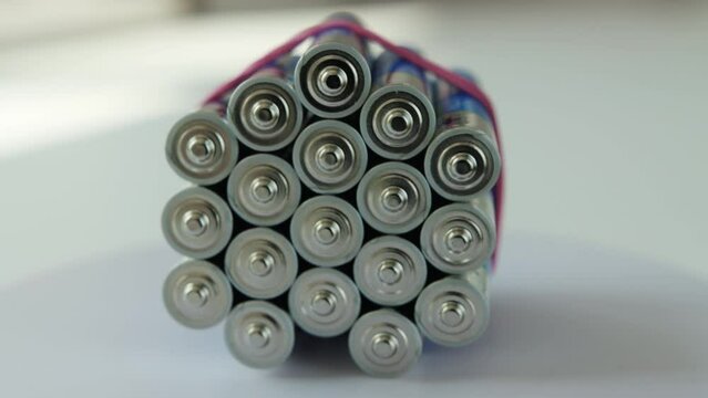 a pile of alkaline batteries rotates on a white background. Finger batteries with different polarity. Close-up