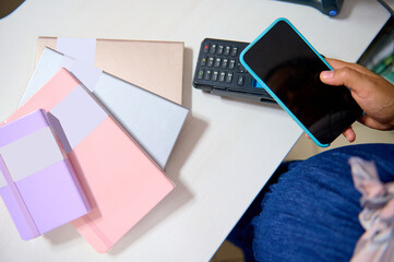 Close-up modern smart mobile phone with blank empty digital screen above a POS terminal on the counter. NFC technology