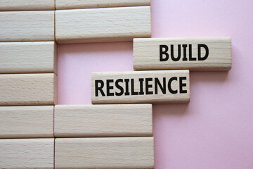 Build resilience symbol. Wooden blocks with words Build resilience. Beautiful pink background. Business and Build resilience concept. Copy space.