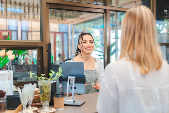 Smiling waitress wear apron take order talk to clients serving restaurant guests choosing food drinks menu in cafe coffeehouse bar, waiting staff, good customer service, cashier serving customers