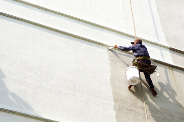 painter hanging on white building