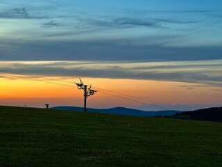 Fototapeta na wymiar Dormant Giants: Industrial Silhouettes of the Ski Lifts Against a Tranquil Sunset in the Vosges Mountains