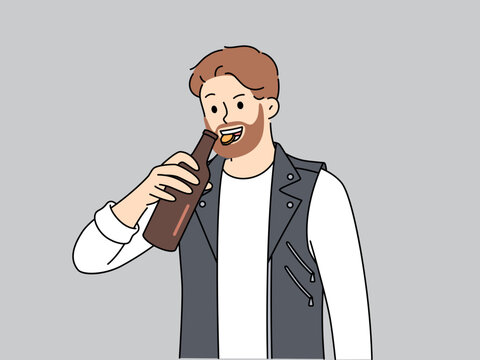 Brutal man opens bottle of beer with teeth and smiles, suffering from alcohol addiction. Young bearded guy in leather vest drinks beer enjoying taste of refreshing intoxicating drink