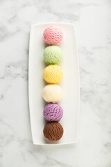 Set of various ice cream scoops on white marble background, top view
