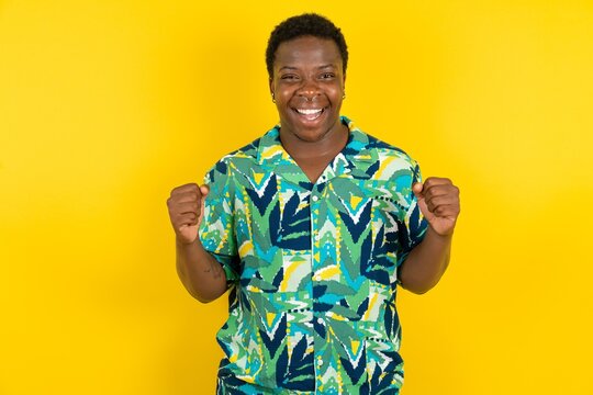 Fototapeta Young latin man wearing hawaiian shirt over yellow background celebrating surprised and amazed for success with arms raised and open eyes. Winner concept.