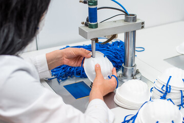The girl works in a factory for the production of medical masks with nanofibre and solder loops...