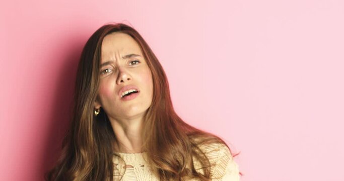 Charismatic young woman  angrily calls someone, with her finger forward and a gesture of coming and is ready to rag isolated over pink background. Hey you, come to me!