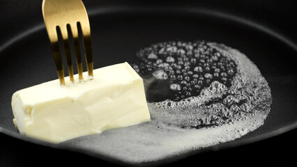 Cube of butter melting sizzling. Butter melting sizzling in frying pan 