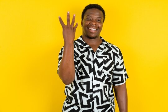 Young latin man wearing printed shirt over yellow background smiling and looking friendly, showing number four or fourth with hand forward, counting down