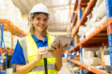 Worker working in large warehouse holding paper chart check list checking the material compare with the boxes wrapped with plastic keep on wooden pallet ready to ship to customer