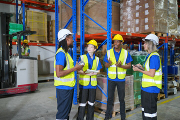 Worker working in large warehouse holding paper chart check list checking the material compare with the boxes wrapped with plastic keep on wooden pallet ready to ship to customer