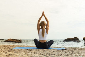 The girl does yoga in nature, near the sea