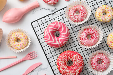 Donuts on grid, balloon and cutlery on marble background, top view