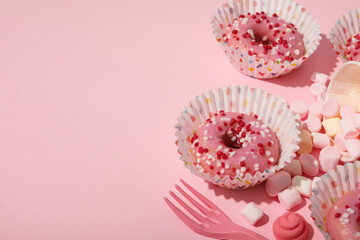 Donuts, marshmallows and cutlery on pink background, space for text