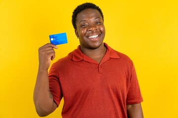 Close up photo of optimistic Young latin man wearing red t-shirt over yellow background hold card