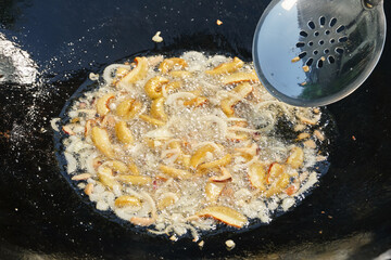 Sliced Porcini mushrooms and onions in boiling oil on frying pan. Preparing food outdoors. Shallow...