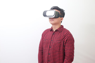 Portrait of Asian man in red plaid shirt using Virtual Reality (VR) glasses and looking up. Isolated image with copy space on white background