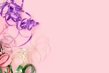 Multicolored ribbons on a pink pastel background. Festive concept with place for text. Selective focus.