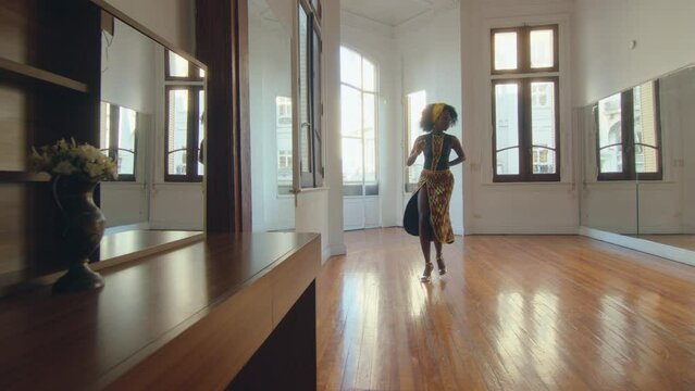Young beautiful black female dancer in stage clothes practicing tango steps during rehearsal in a dance studio