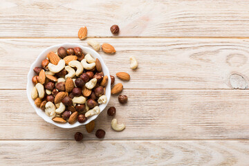 Assortment of nuts in wooden bowl on colored table. Cashew, hazelnuts, walnuts, almonds. Mix of nuts Top view with copy space