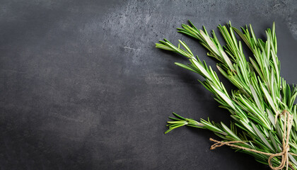 Rosemary herbs on dark stone background. Copy space for menu or recipe. Flat Lay.